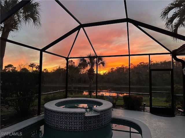 patio terrace at dusk featuring a swimming pool with hot tub, a lanai, and central AC unit