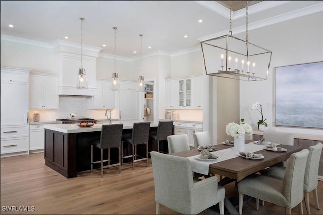 dining area with hardwood / wood-style flooring, ornamental molding, and sink