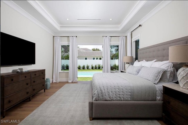 bedroom featuring a raised ceiling, ornamental molding, and light hardwood / wood-style flooring