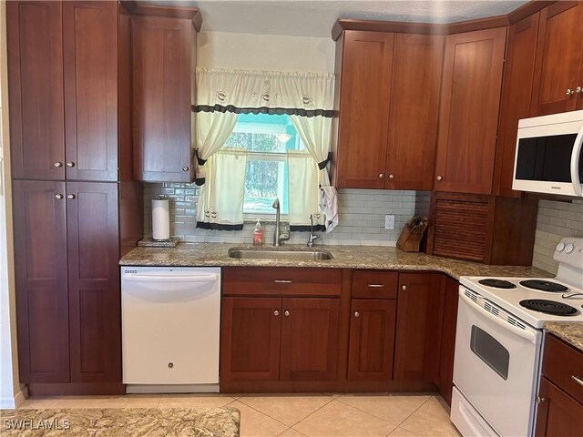 kitchen featuring white appliances, light stone counters, backsplash, and a sink