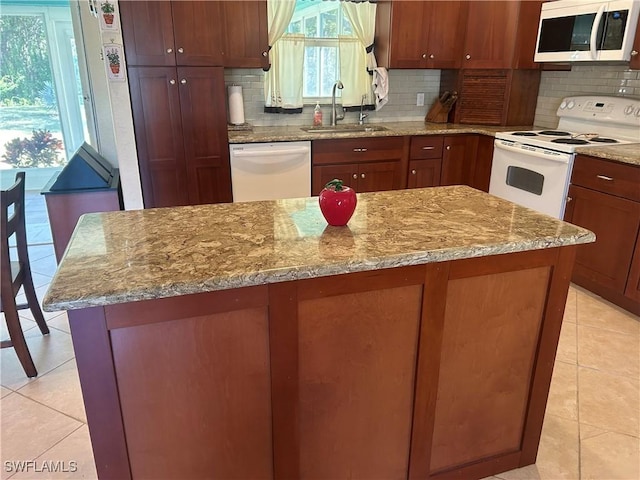 kitchen with tasteful backsplash, white appliances, a sink, and light stone countertops