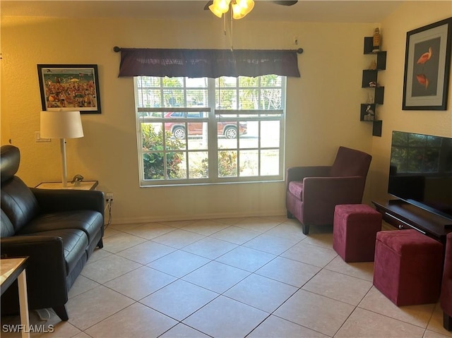 living area featuring light tile patterned floors, ceiling fan, and baseboards