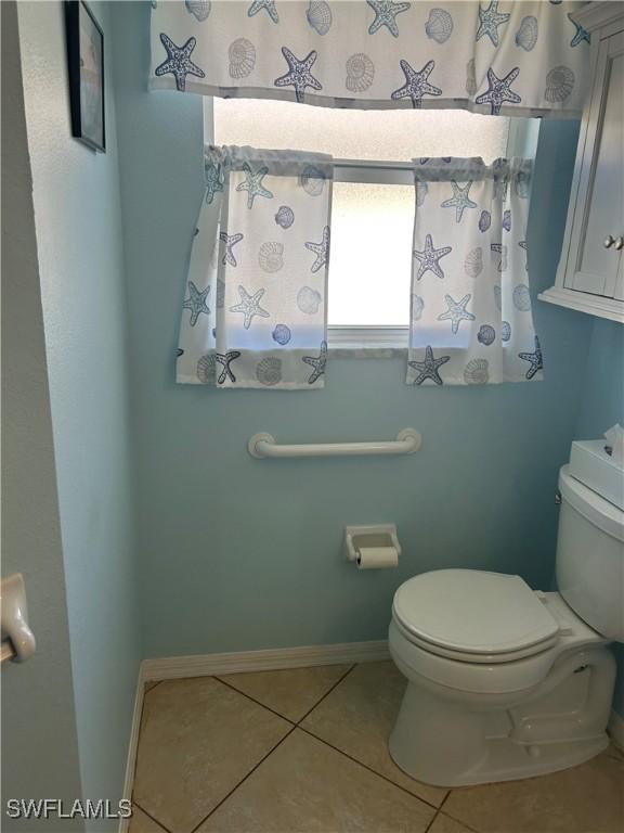 bathroom with tile patterned flooring, baseboards, and toilet