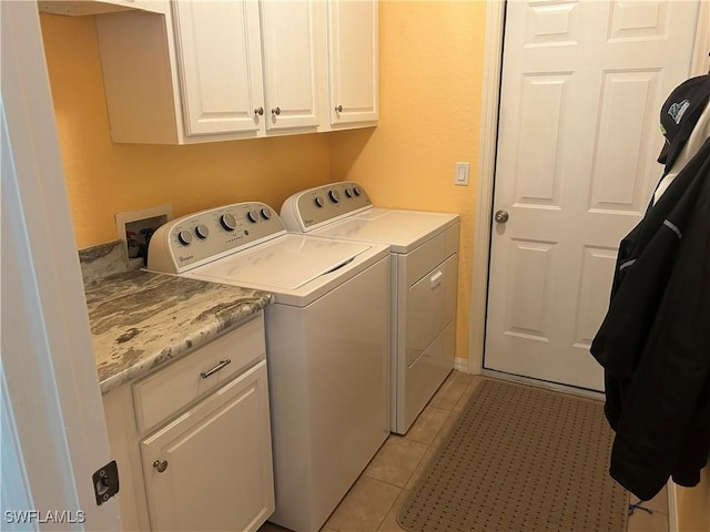 washroom featuring washer and dryer, cabinet space, and light tile patterned flooring