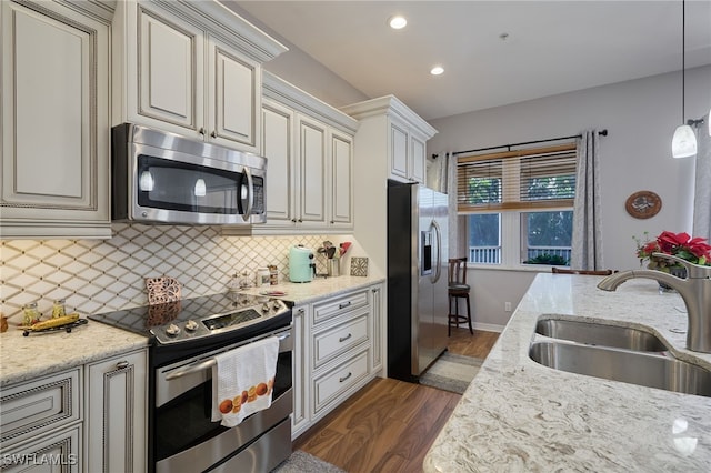 kitchen featuring sink, backsplash, dark hardwood / wood-style flooring, light stone counters, and stainless steel appliances