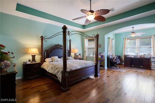 bedroom featuring ceiling fan, dark hardwood / wood-style floors, and a raised ceiling