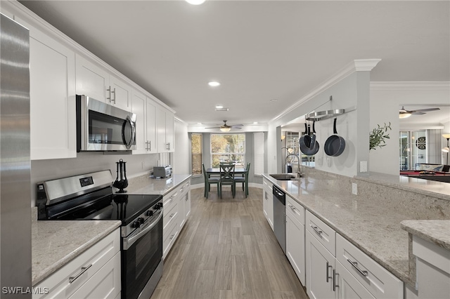 kitchen featuring light stone counters, stainless steel appliances, sink, and white cabinets