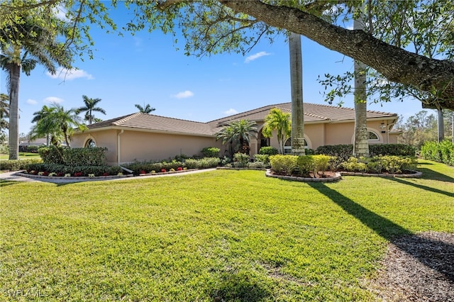 view of front of home featuring a tiled roof, a front lawn, and stucco siding