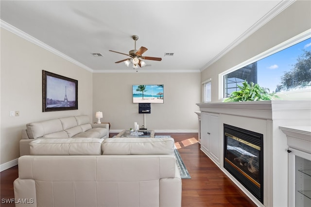 living area featuring dark wood-style floors, baseboards, a glass covered fireplace, and crown molding