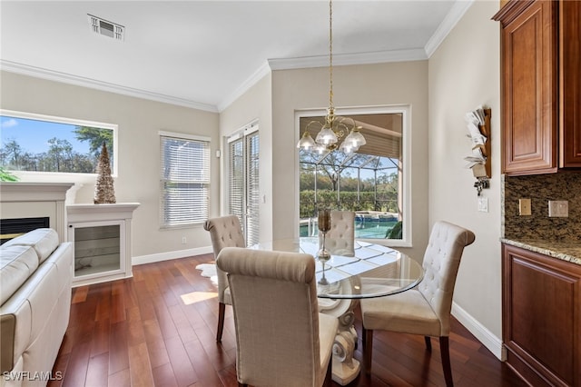 dining room featuring dark wood-type flooring, a fireplace, visible vents, and crown molding