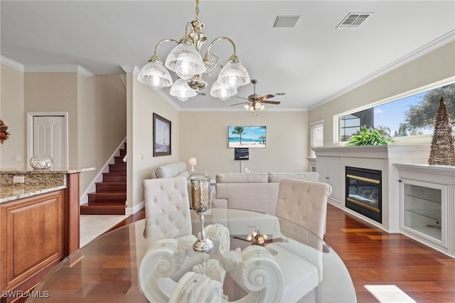 dining room with ornamental molding, dark wood-type flooring, a glass covered fireplace, and visible vents