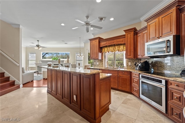 kitchen featuring brown cabinetry, a kitchen island, appliances with stainless steel finishes, hanging light fixtures, and backsplash