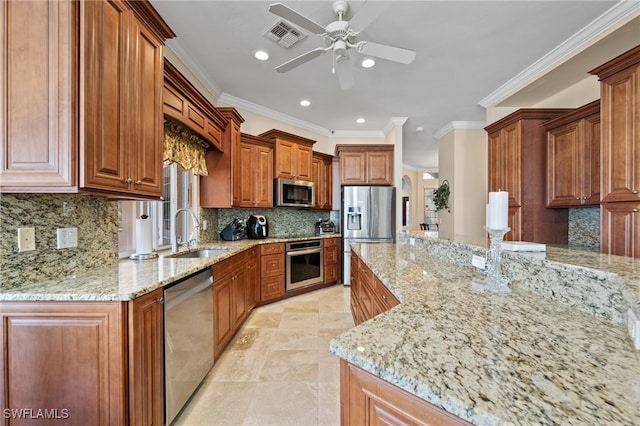 kitchen featuring brown cabinets, appliances with stainless steel finishes, a sink, and light stone countertops