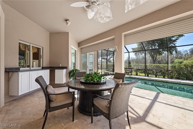 dining area with a sunroom, stone tile floors, and ceiling fan