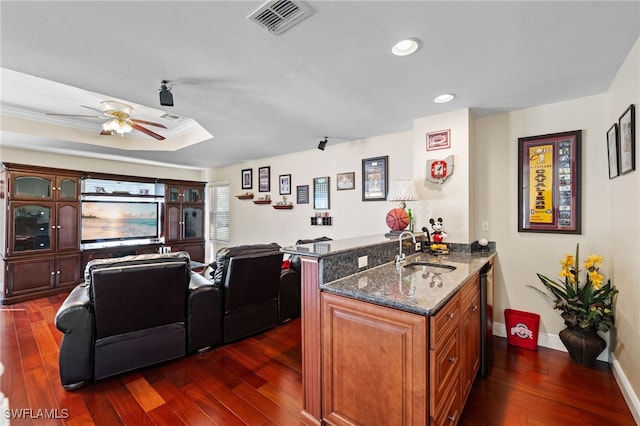 kitchen featuring a peninsula, dark wood-style floors, dark stone countertops, and a sink