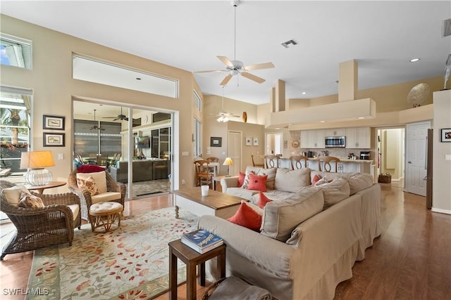 living room with wood finished floors, visible vents, and a ceiling fan