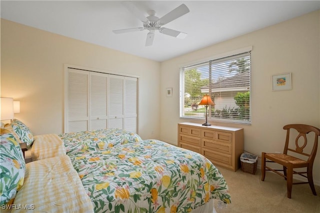 bedroom featuring a ceiling fan, a closet, and light colored carpet