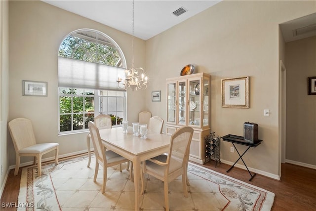 dining area featuring baseboards, wood finished floors, visible vents, and an inviting chandelier