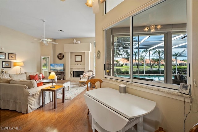 interior space with ceiling fan, a tiled fireplace, wood finished floors, and visible vents