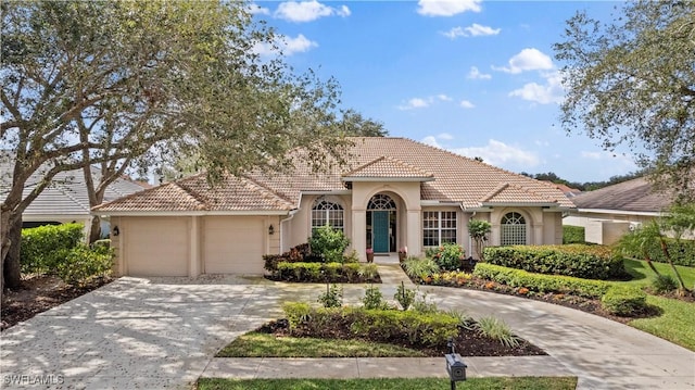 mediterranean / spanish home with a garage, a tile roof, driveway, and stucco siding