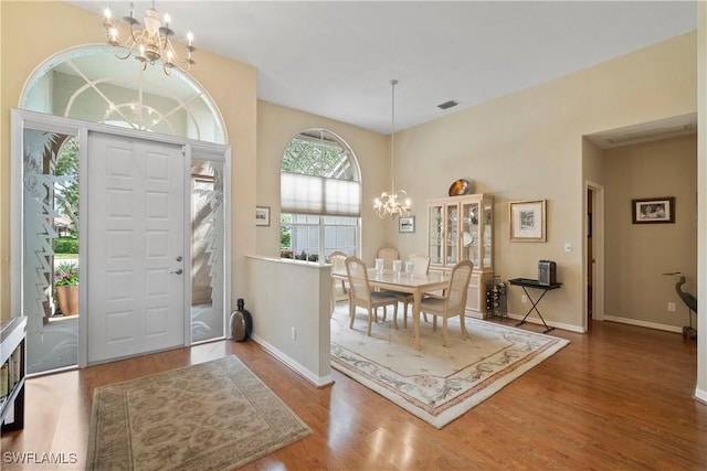 entrance foyer with a chandelier, visible vents, baseboards, and wood finished floors