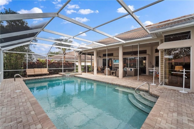 view of pool with ceiling fan, glass enclosure, a patio, a pool with connected hot tub, and an outdoor living space