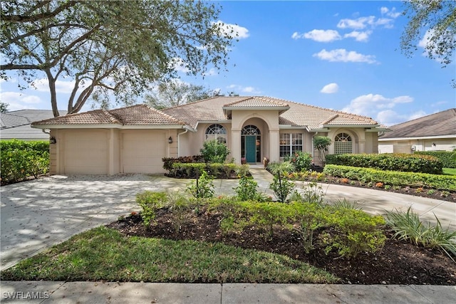 mediterranean / spanish-style home with a garage, a tile roof, driveway, and stucco siding