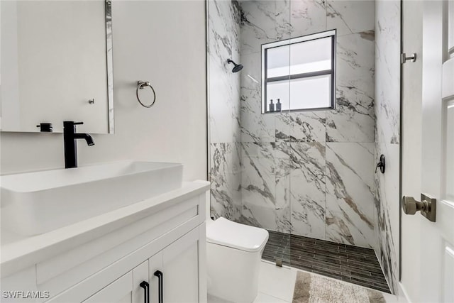 bathroom featuring toilet, tiled shower, and vanity