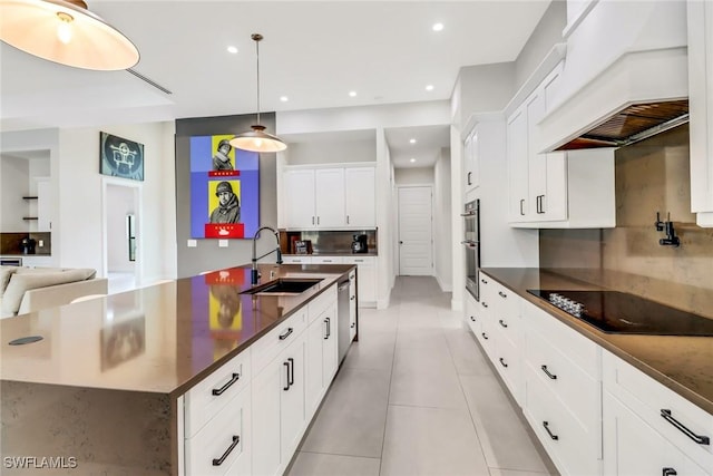 kitchen with stainless steel appliances, decorative light fixtures, a large island with sink, sink, and custom exhaust hood