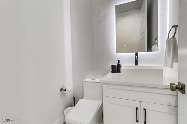 bathroom with vanity, tile walls, toilet, and tasteful backsplash