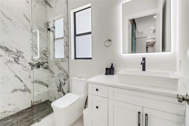 bathroom with vanity, tiled shower, and toilet