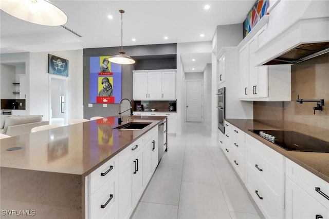 kitchen featuring a large island, stainless steel appliances, decorative light fixtures, sink, and custom range hood