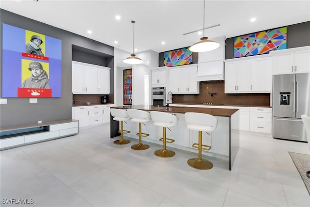 kitchen with a center island with sink, white cabinets, stainless steel appliances, and pendant lighting