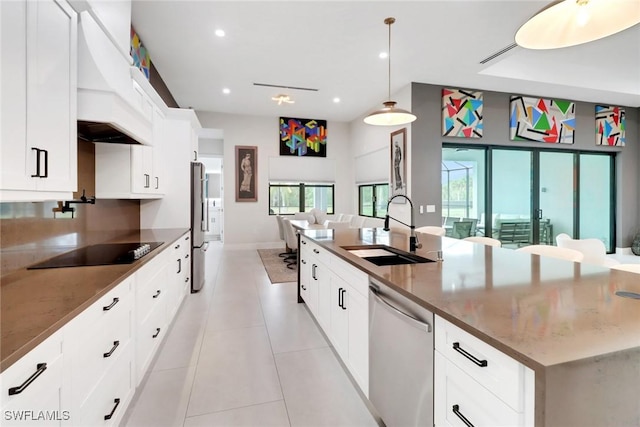 kitchen featuring white cabinetry, stainless steel appliances, sink, dark stone countertops, and pendant lighting