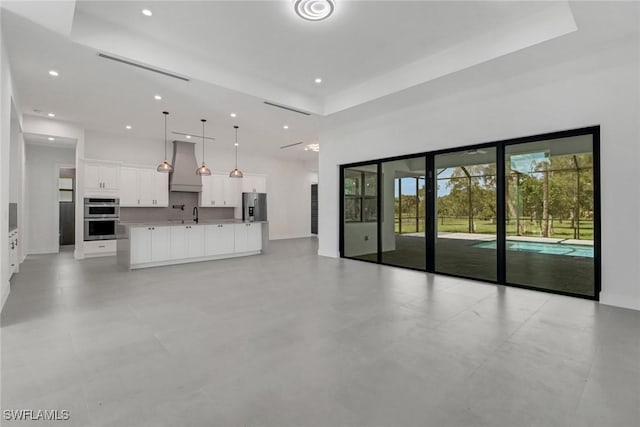 unfurnished living room with sink, a towering ceiling, and a raised ceiling