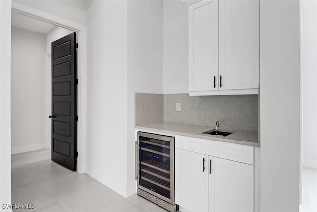 bar with white cabinetry, sink, beverage cooler, and backsplash