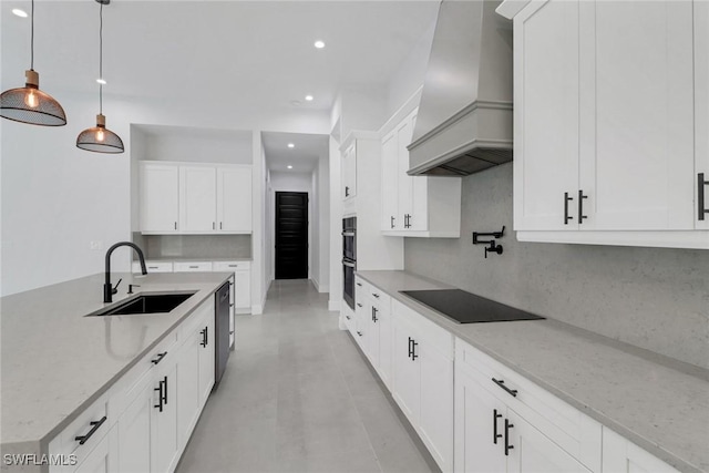 kitchen featuring hanging light fixtures, black appliances, light stone countertops, premium range hood, and sink