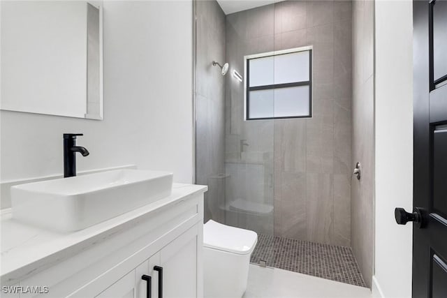 bathroom featuring toilet, vanity, and tiled shower