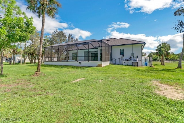 back of property featuring a lanai and a lawn