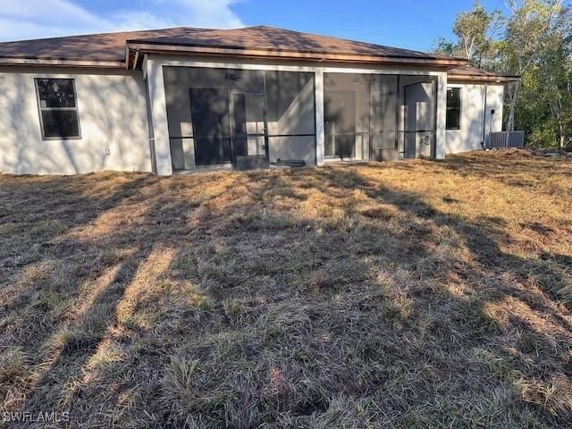 rear view of house featuring a sunroom and a yard