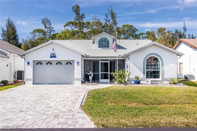 single story home with decorative driveway, stucco siding, a garage, cooling unit, and a front lawn