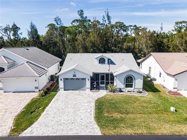 single story home with an attached garage, cooling unit, decorative driveway, a front lawn, and stucco siding