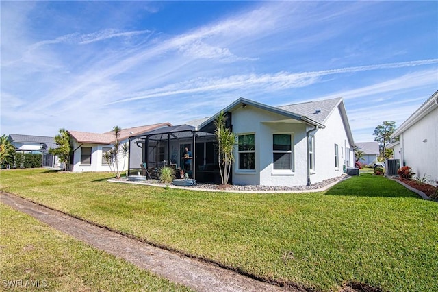 rear view of house with a lanai, a yard, central AC unit, and stucco siding