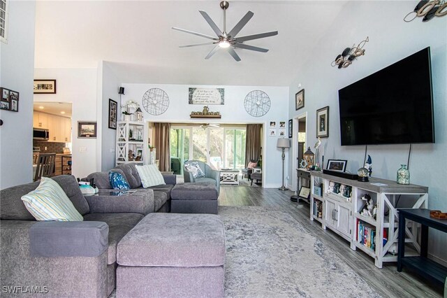 living room featuring ceiling fan, hardwood / wood-style floors, and a towering ceiling