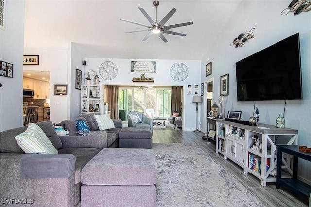 living room with a towering ceiling, ceiling fan, and wood finished floors