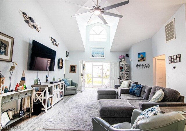 living room with ceiling fan, high vaulted ceiling, and light hardwood / wood-style flooring