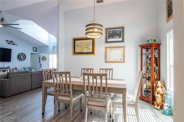 dining room with hardwood / wood-style flooring, ceiling fan, and a high ceiling