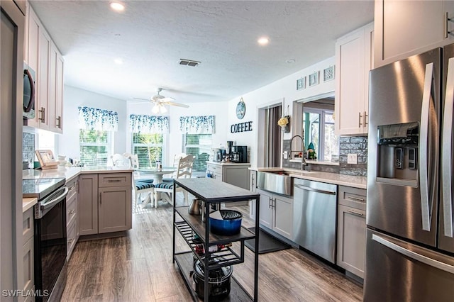 kitchen featuring a healthy amount of sunlight, appliances with stainless steel finishes, gray cabinets, and dark wood finished floors