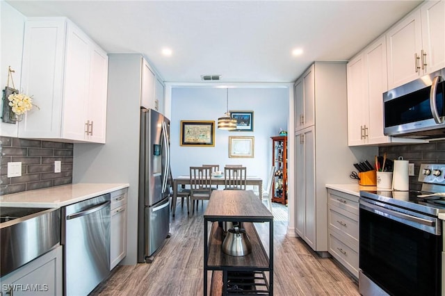 kitchen with stainless steel appliances, light countertops, light wood-style floors, and tasteful backsplash