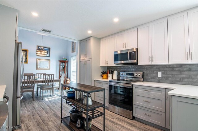 kitchen featuring stainless steel appliances, hanging light fixtures, gray cabinets, and backsplash